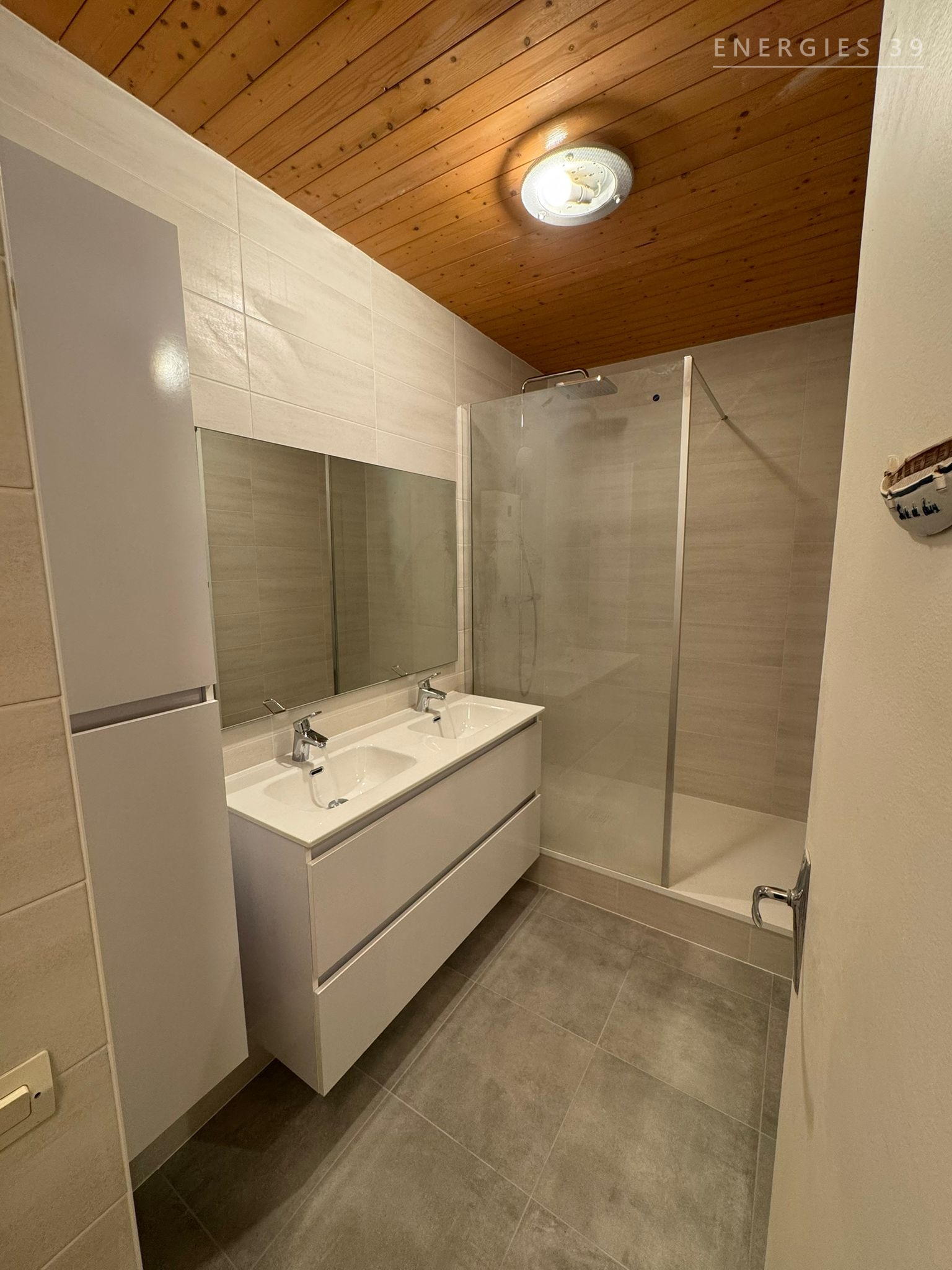 Salle de bain chaleureuse avec plafond bois et double vasque