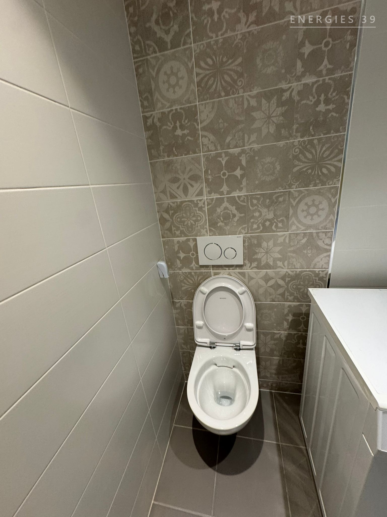 WC suspendu avec mur d'accent en carreaux à motifs ornementaux