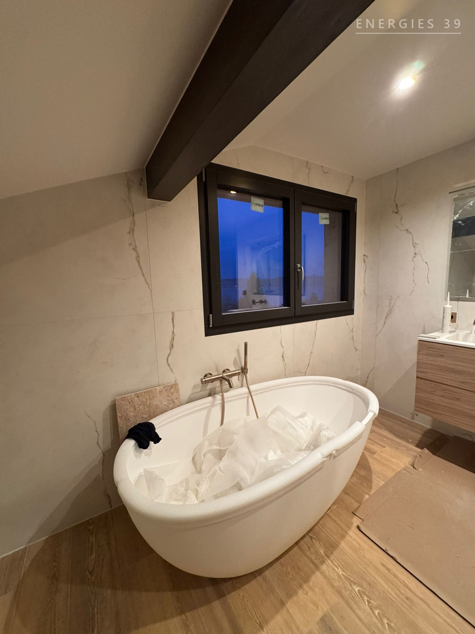 Baignoire îlot ovale sous combles avec murs en marbre