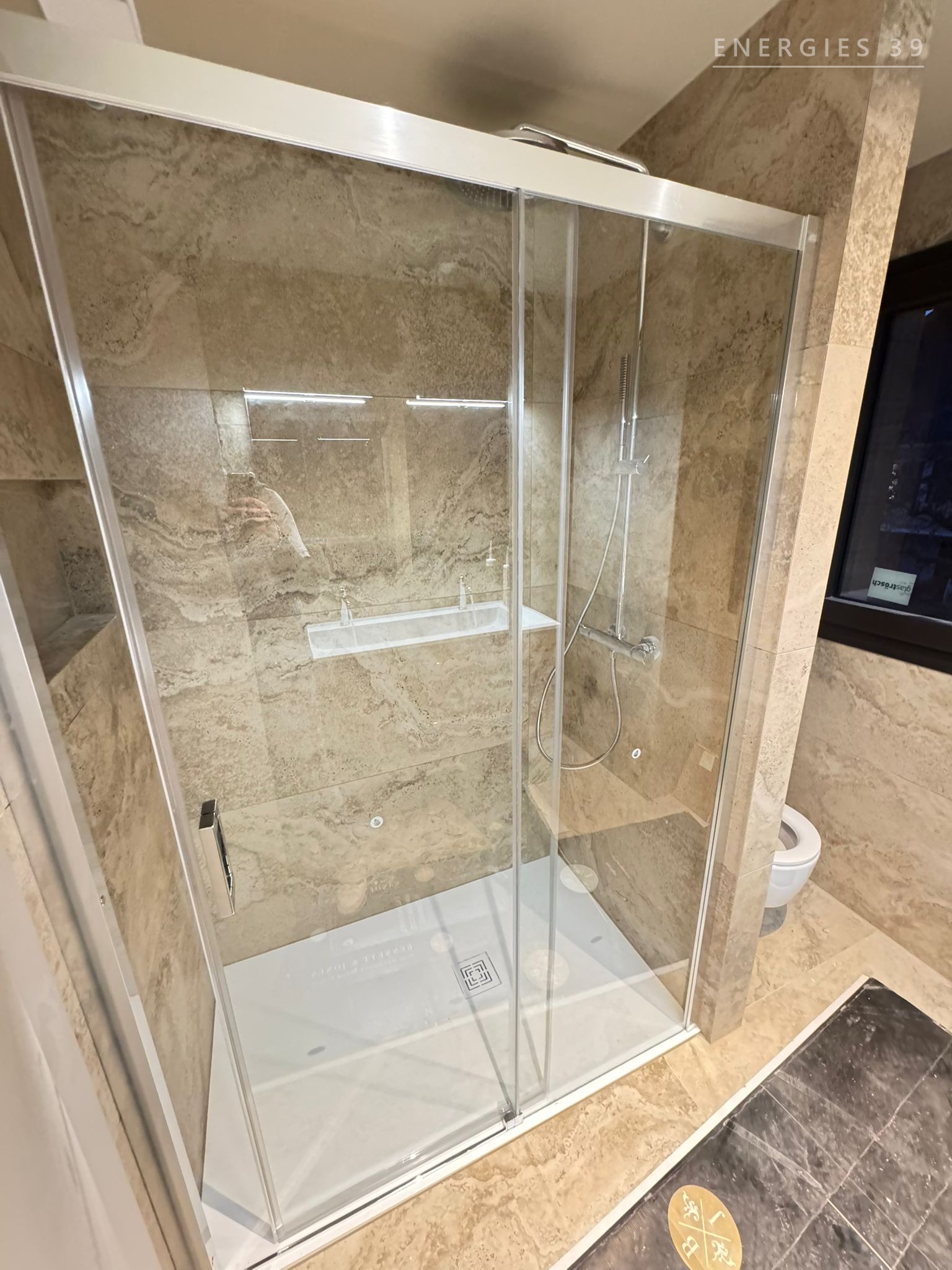 Grande douche en travertin avec portes coulissantes en verre